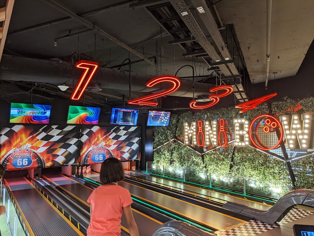A child enjoys mini-bowling at Timezone Westgate, featuring vibrant neon signs and screens.
