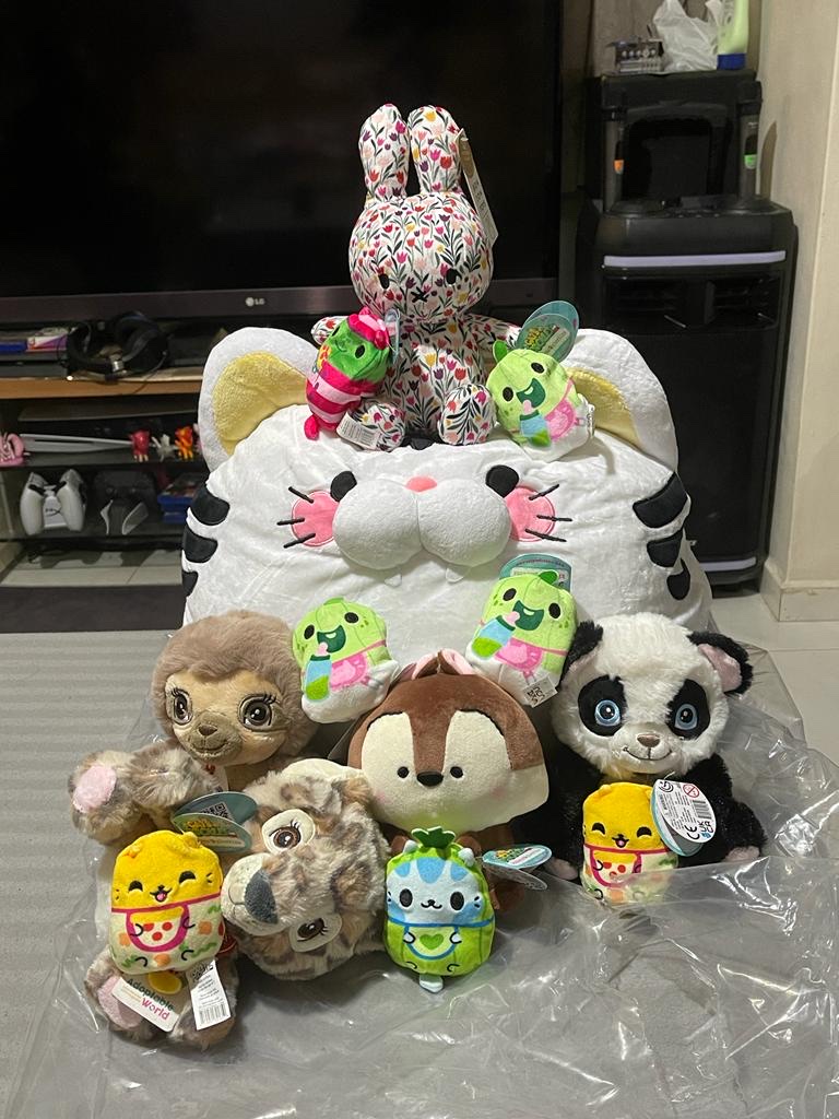 A vibrant collection of plush toys, including a large white cat, a floral bunny, and various animal characters.