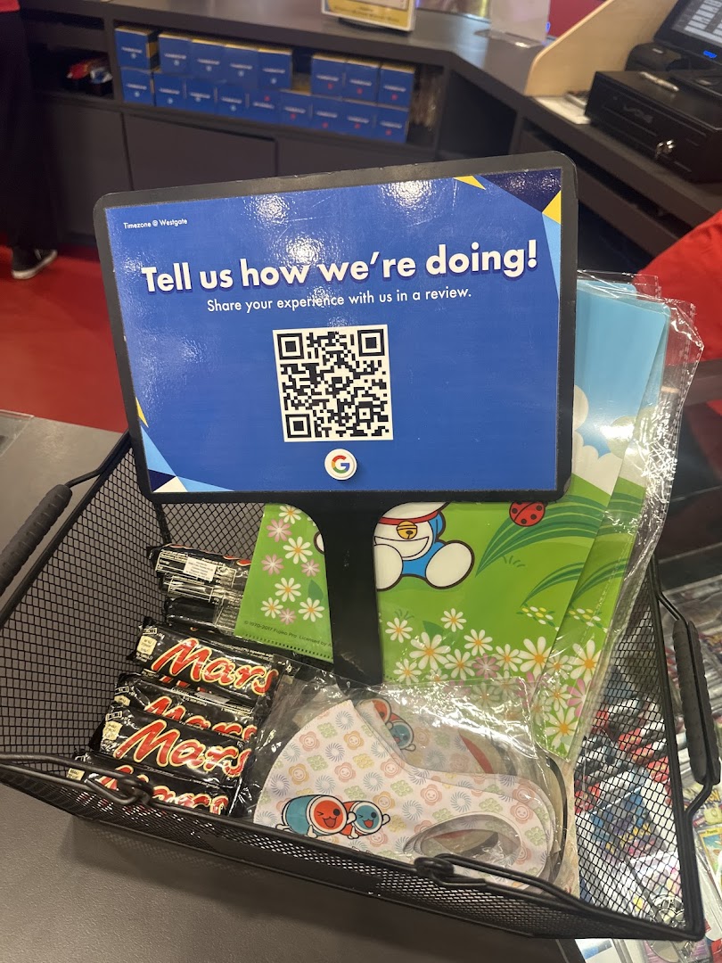 A counter display with a customer feedback sign, QR code, and merchandise like Mars bars and masks.