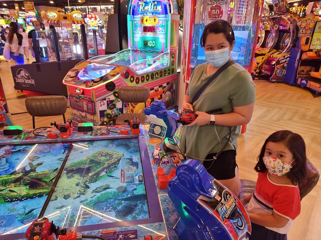 An adult and child play an interactive fishing arcade game at Timezone, surrounded by other colorful machines.