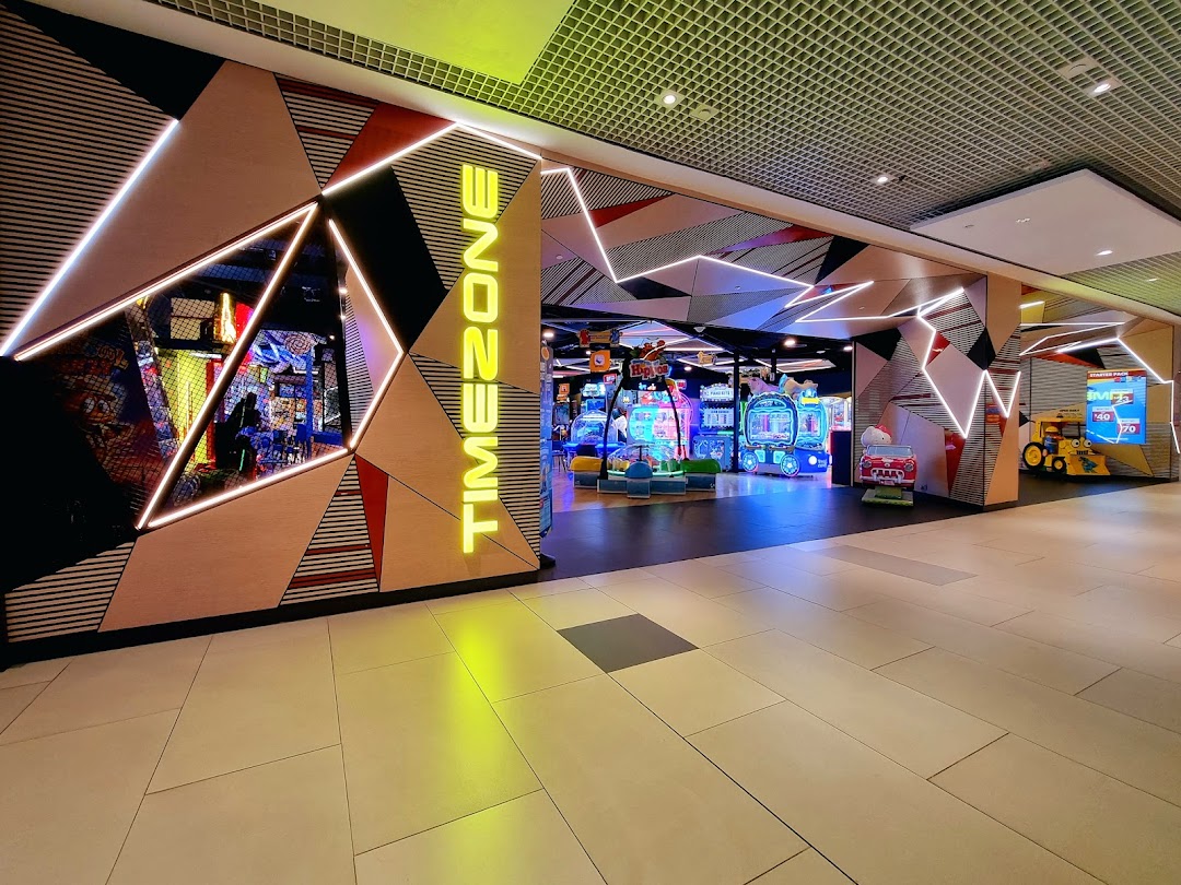 Vibrant entrance of Timezone arcade, featuring neon lights and a glimpse of games inside.