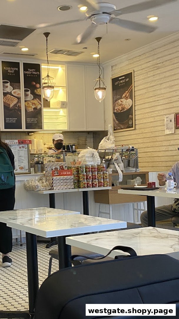 An interior view of Toast Box, showing the counter, staff, marble tables, and promotional posters.