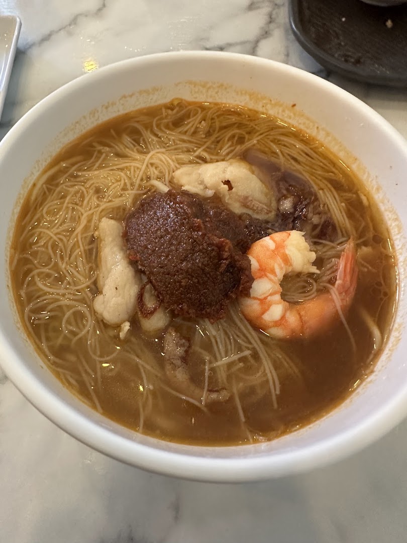 A close-up of a delicious bowl of noodles with shrimp, fish cake, and a rich sauce from Toast Box.