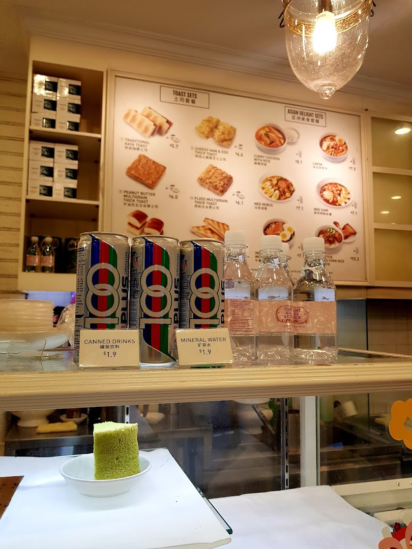 An interior shot of Toast Box, featuring a menu board with toast and Asian delight sets, alongside canned drinks and mineral water.