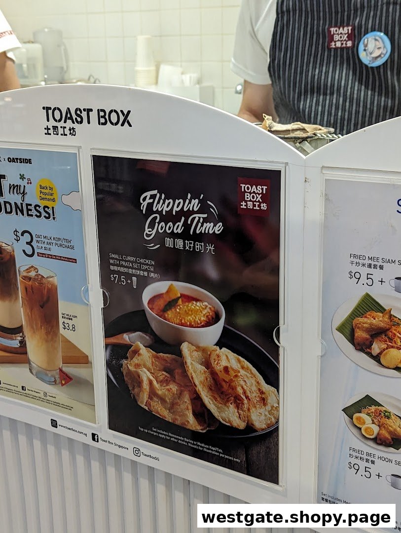 A close-up of Toast Box's menu display featuring curry chicken prata, fried noodles, and oat milk drinks.