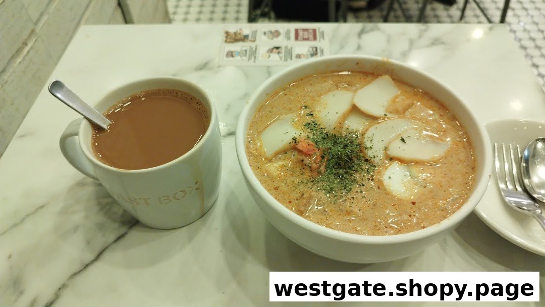 A bowl of laksa and a cup of coffee on a marble table at Toast Box.