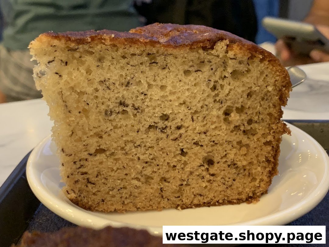 A close-up of a delicious slice of banana bread or cake served on a white plate.