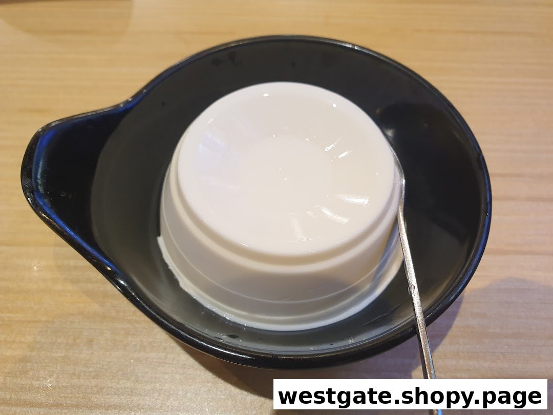 A smooth white dessert, possibly tofu pudding or panna cotta, served in a black bowl with a spoon.