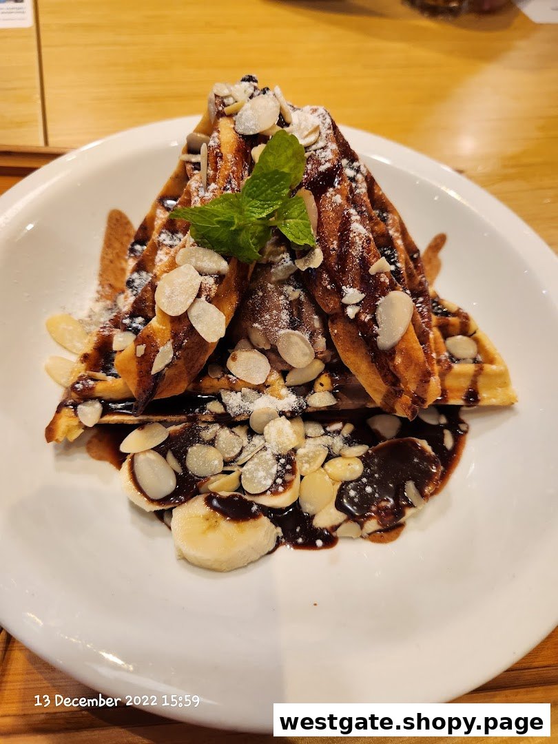 Waffles with chocolate, almonds, powdered sugar, mint, and banana slices on a white plate.