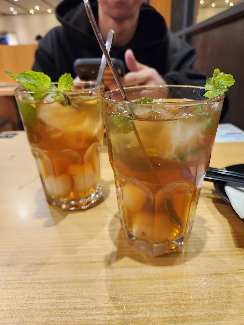 Two refreshing iced drinks with mint and fruit on a wooden table at Tokyo Shokudo.