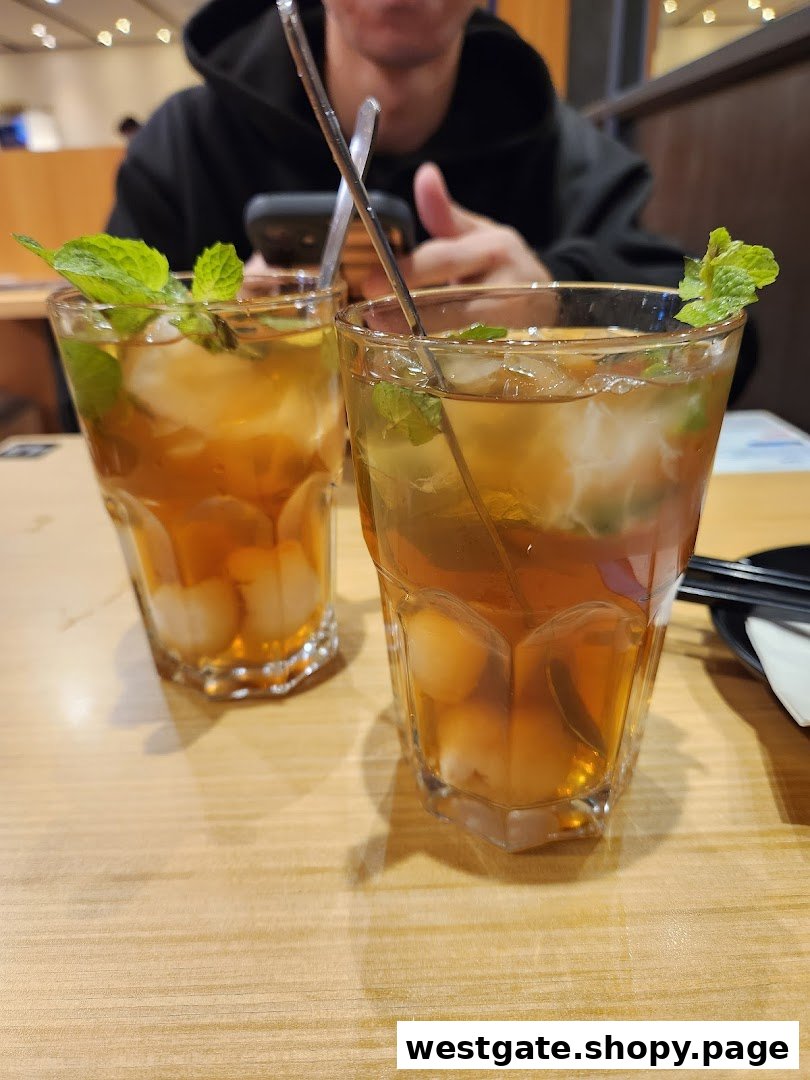 Two refreshing iced drinks with mint and fruit on a wooden table at Tokyo Shokudo.