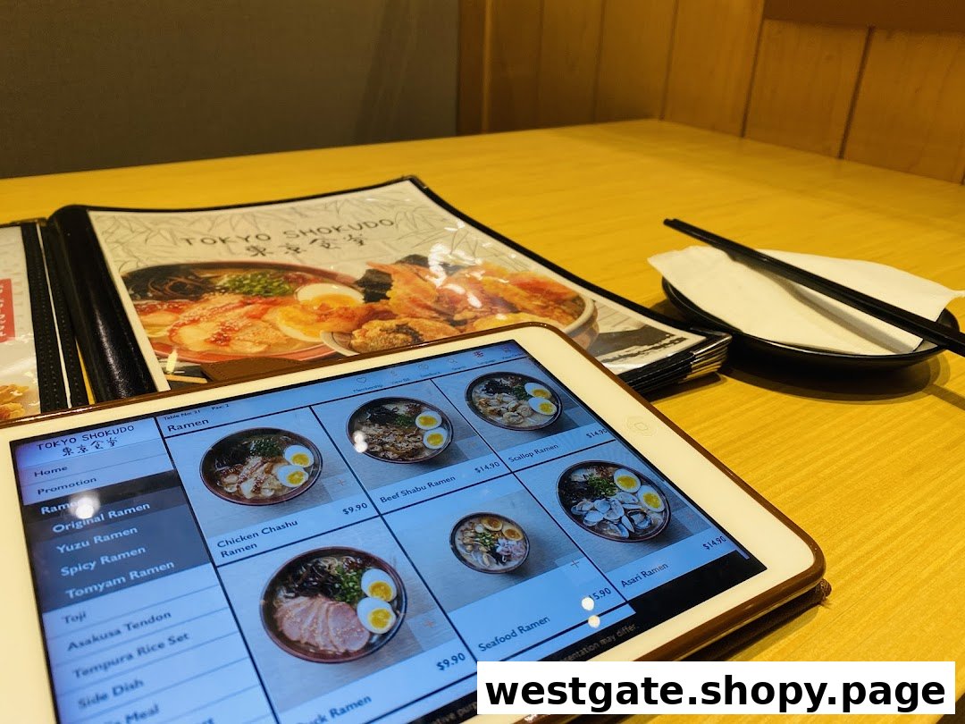 A table setting at Tokyo Shokudo featuring a physical menu and a tablet displaying various ramen dishes.