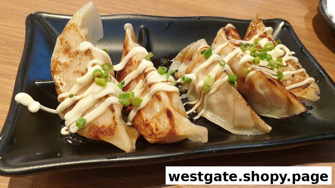 A plate of pan-fried gyoza topped with mayonnaise and chopped spring onions.
