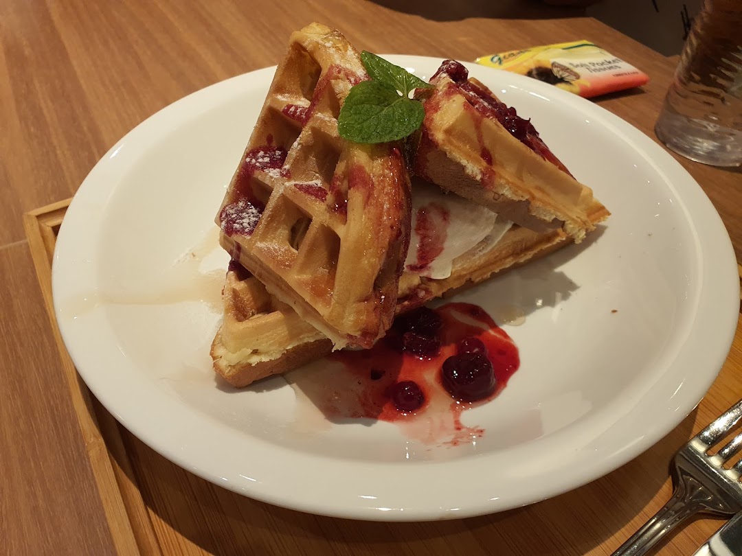 Delicious waffles topped with berries, powdered sugar, and a scoop of ice cream on a white plate.