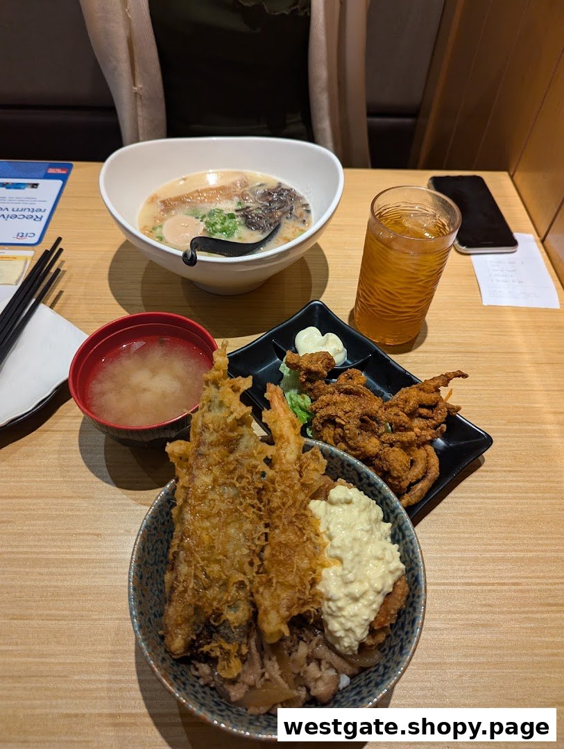 A delicious Japanese meal featuring ramen, tempura donburi, miso soup, and fried soft-shell crab on a wooden table.
