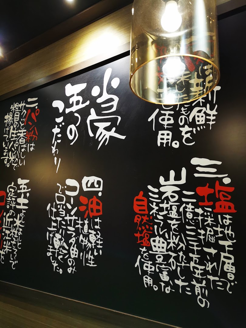 A stylish interior wall with Japanese calligraphy detailing ingredient quality and cooking philosophy.