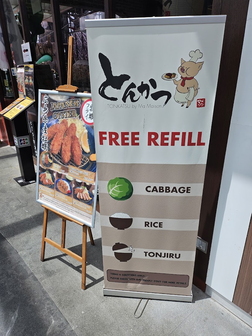 Promotional signs for Tonkatsu by Ma Maison, featuring free refills and Japanese oyster specials at the shop entrance.