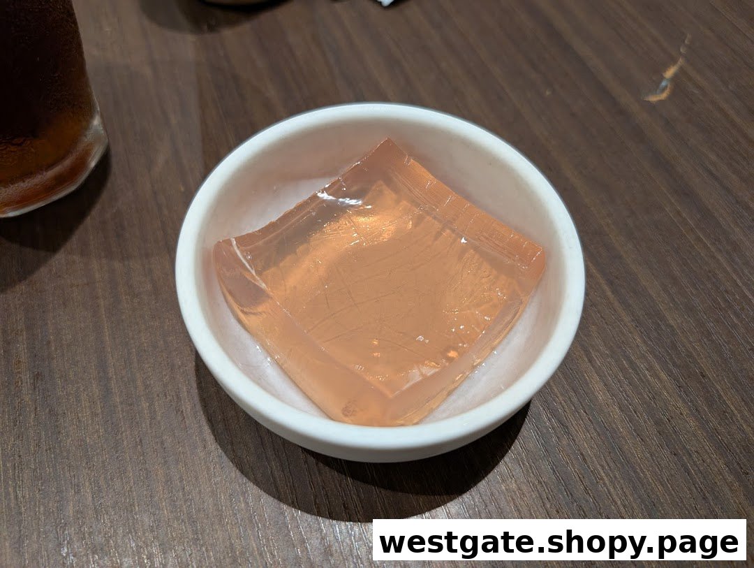 A small white bowl holds a clear, light orange jelly dessert on a wooden table.