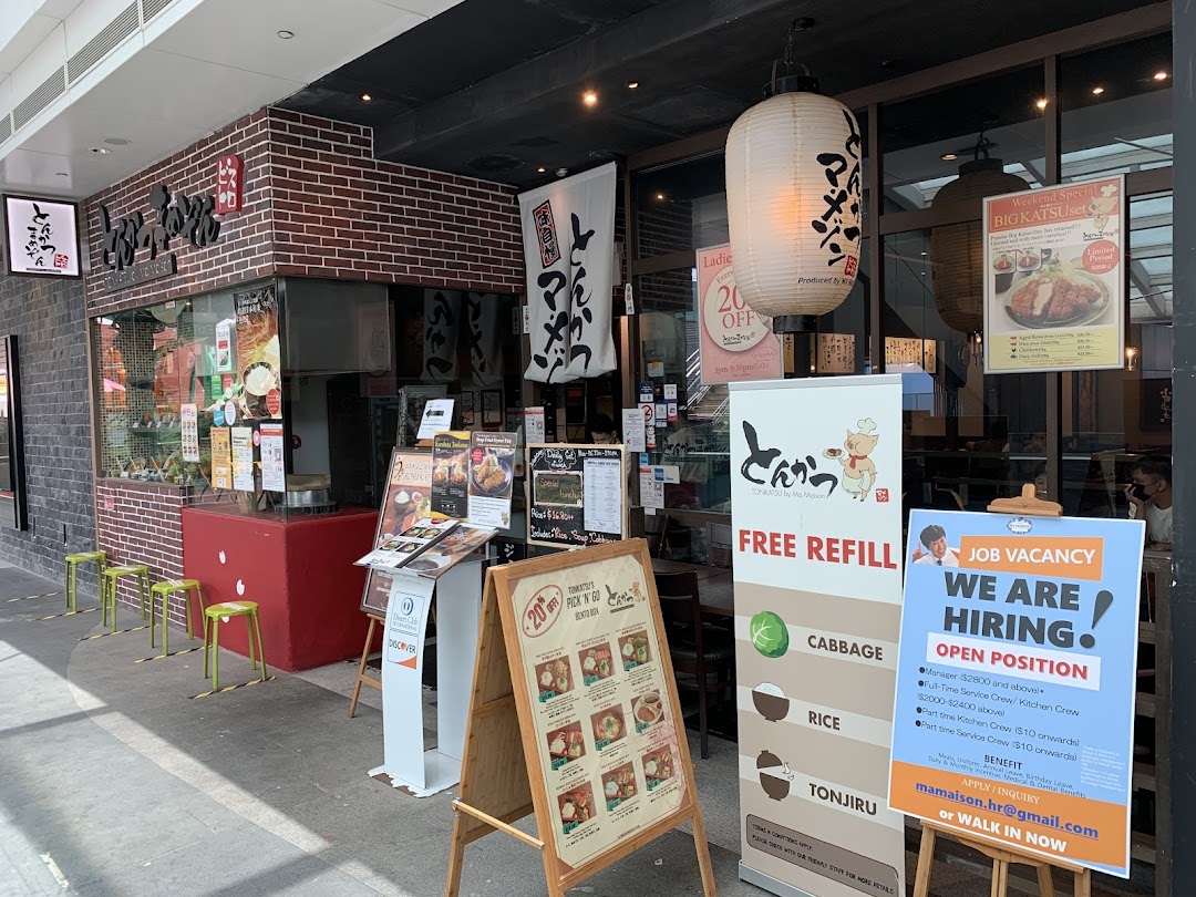 The inviting storefront of Tonkatsu by Ma Maison, featuring promotional signs and Japanese lanterns.