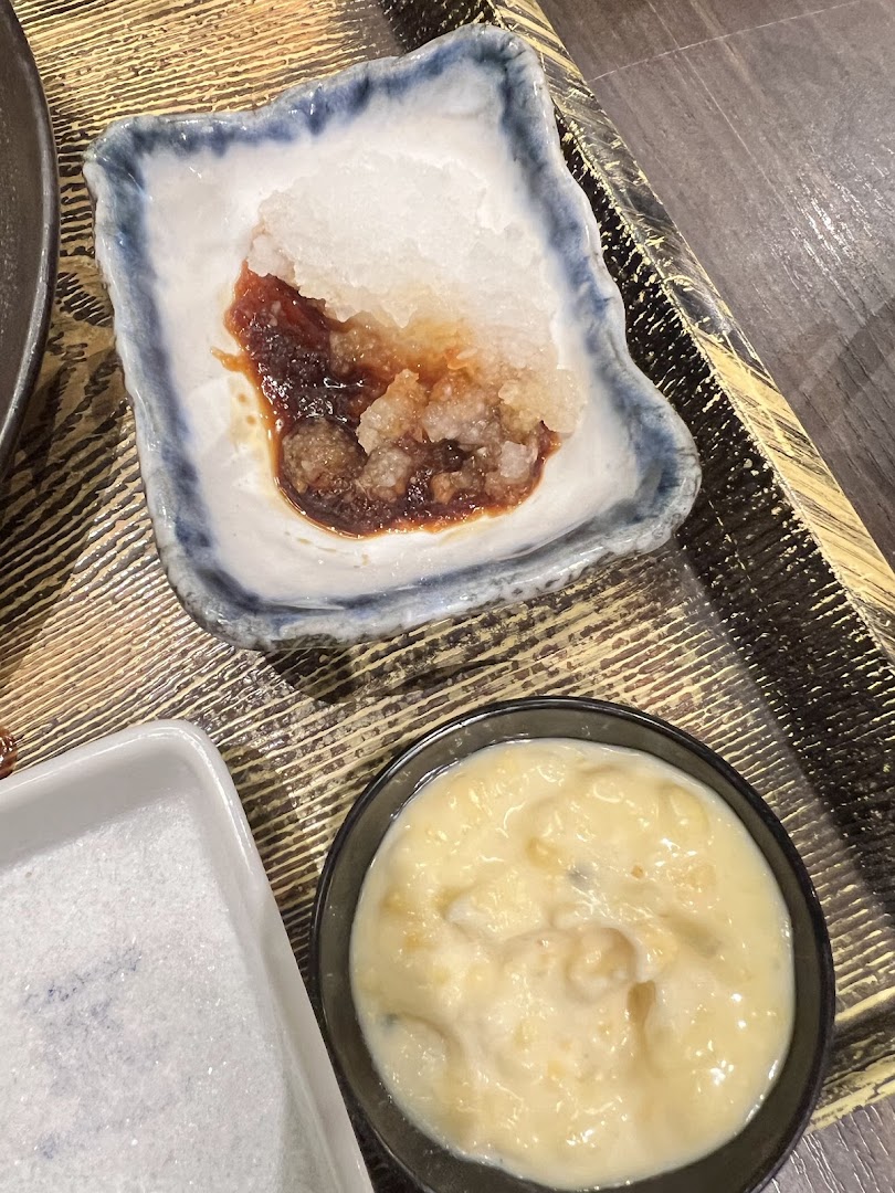 Close-up of various Japanese condiments and sauces on a wooden tray.