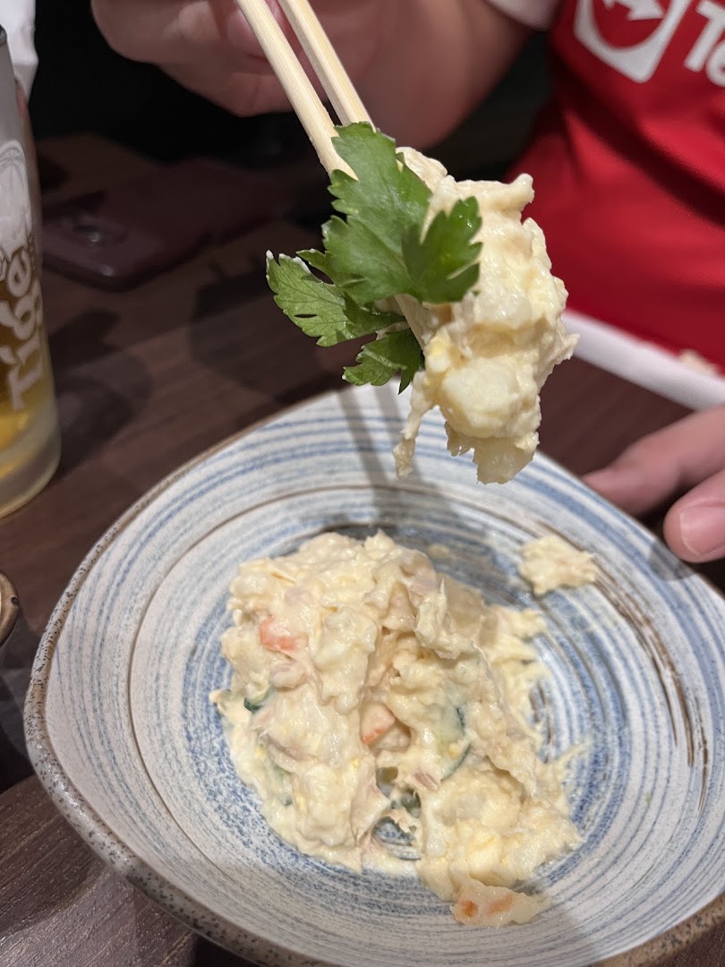 A close-up of creamy potato salad with parsley being served with chopsticks.