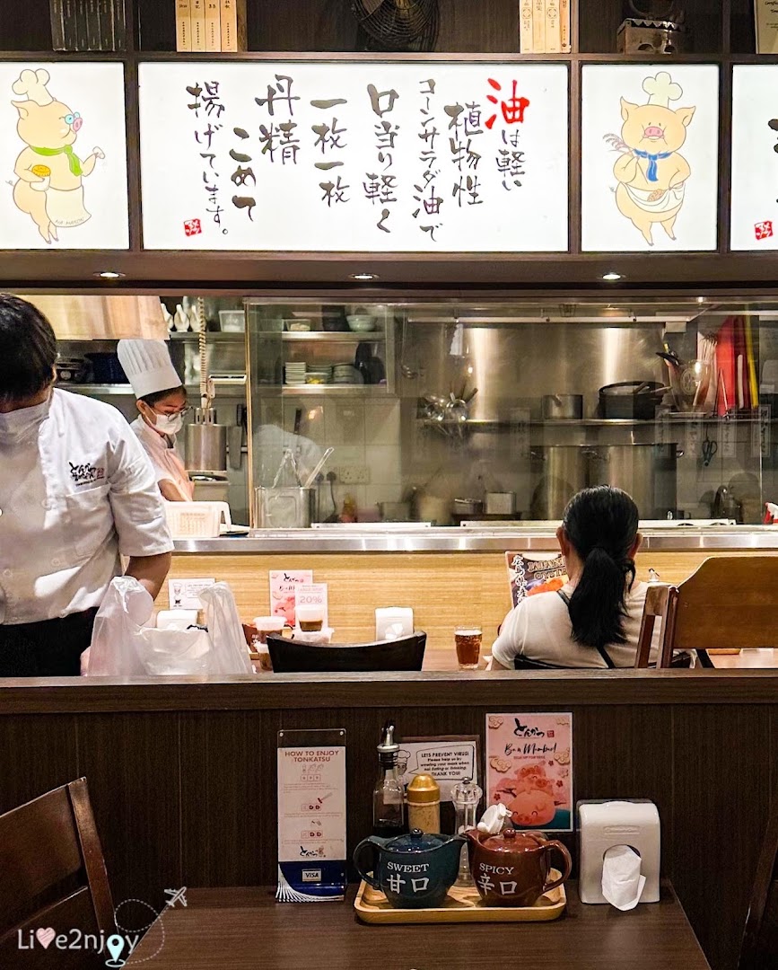 An interior view of Tonkatsu by Ma Maison, featuring the open kitchen and a dining table.