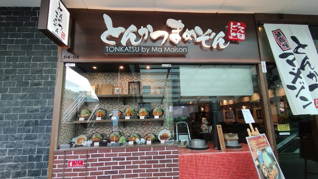 The shopfront of Tonkatsu by Ma Maison, featuring its prominent signage and a display of realistic food models.