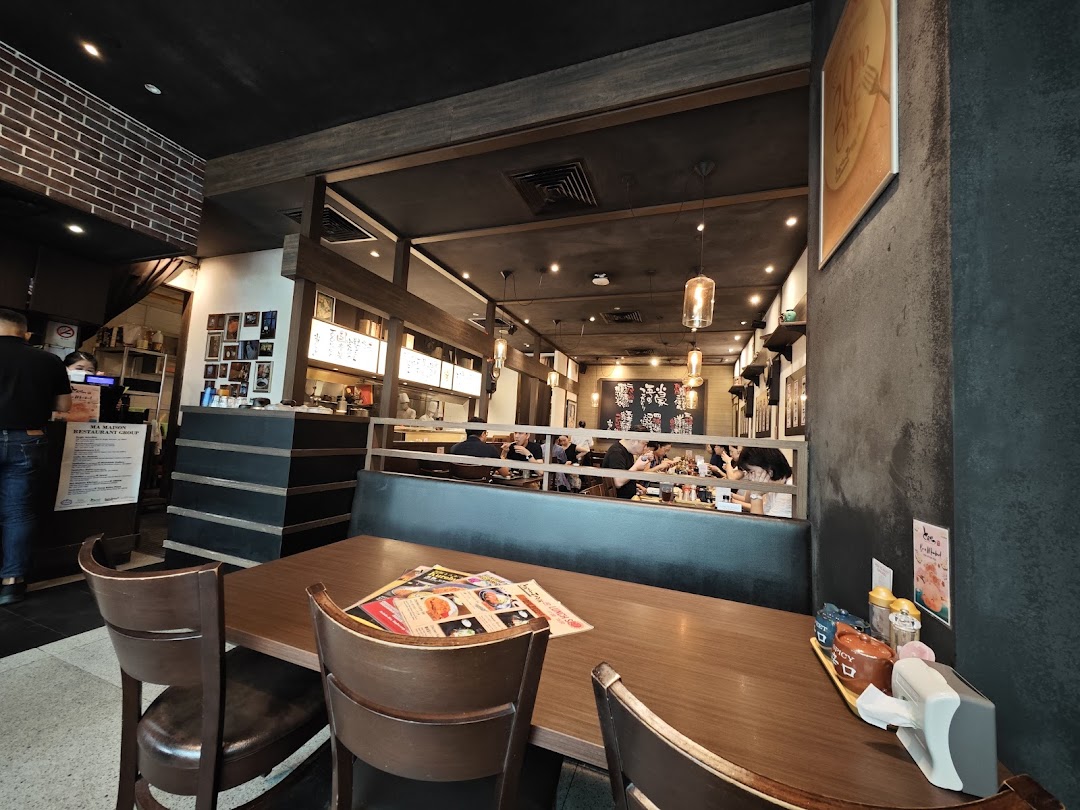 An inviting interior view of Tonkatsu by Ma Maison, featuring dining tables and a cozy ambiance.