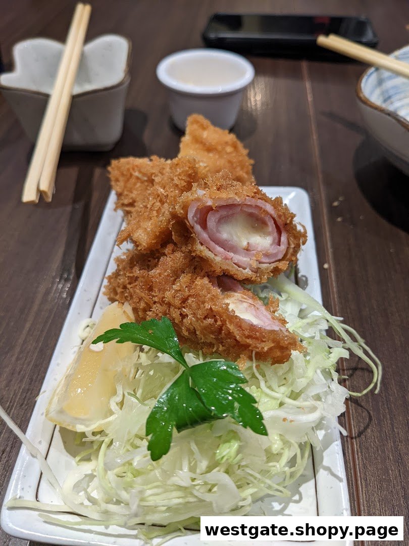 A plate of crispy tonkatsu with ham and melted cheese, served with shredded cabbage and lemon.