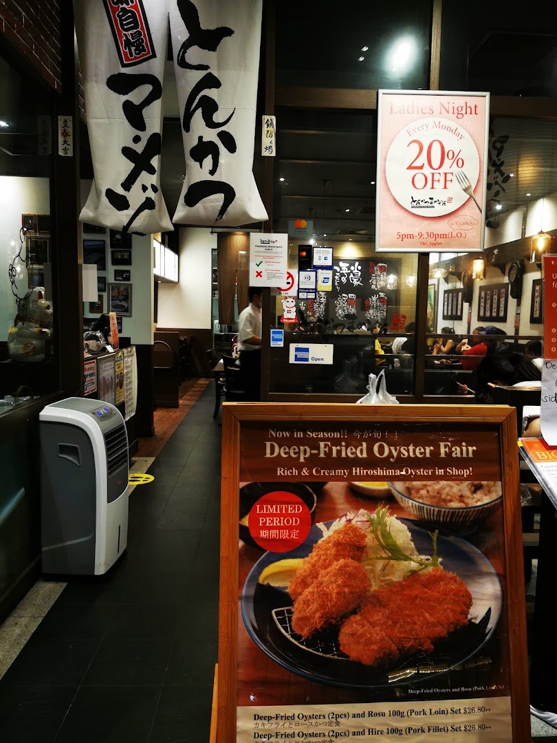 The entrance of Tonkatsu by Ma Maison, featuring promotional displays and a glimpse of the inviting interior.