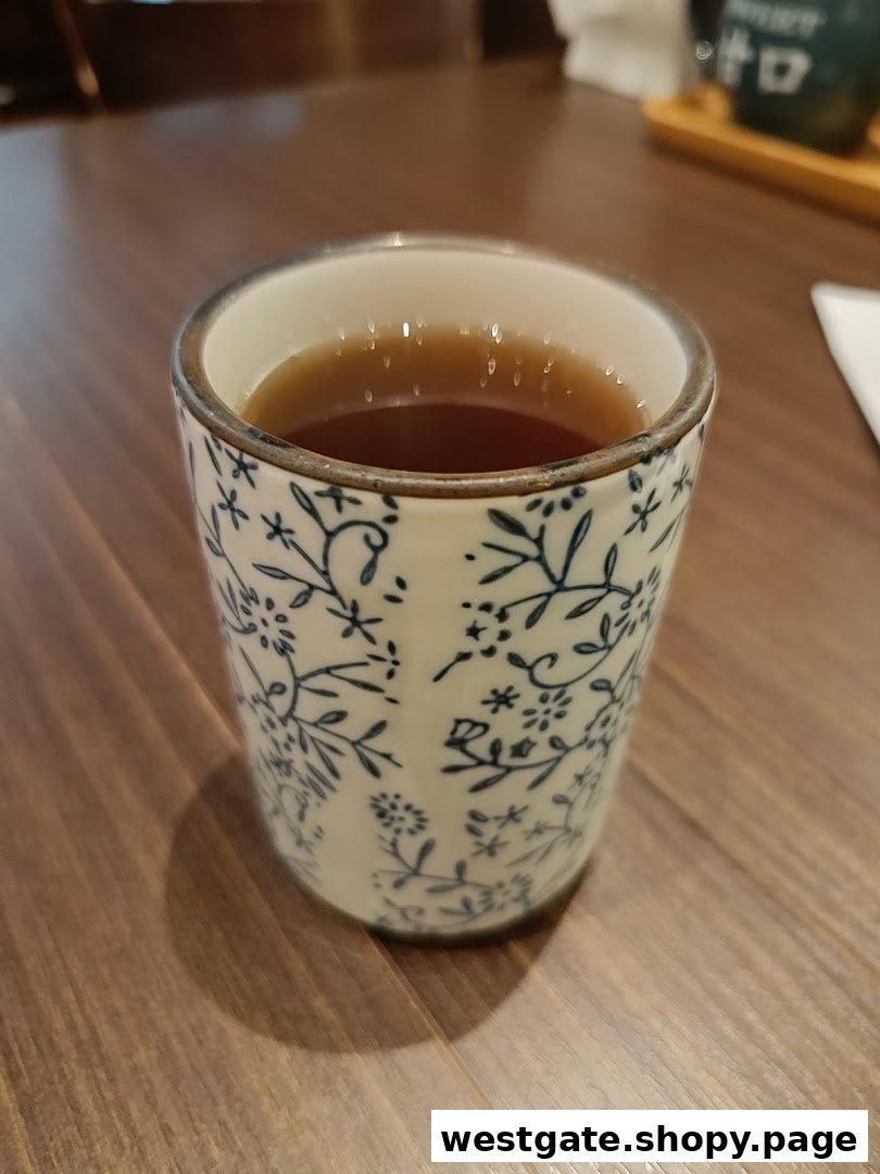 A decorative ceramic cup filled with a warm beverage, likely tea, on a wooden table.