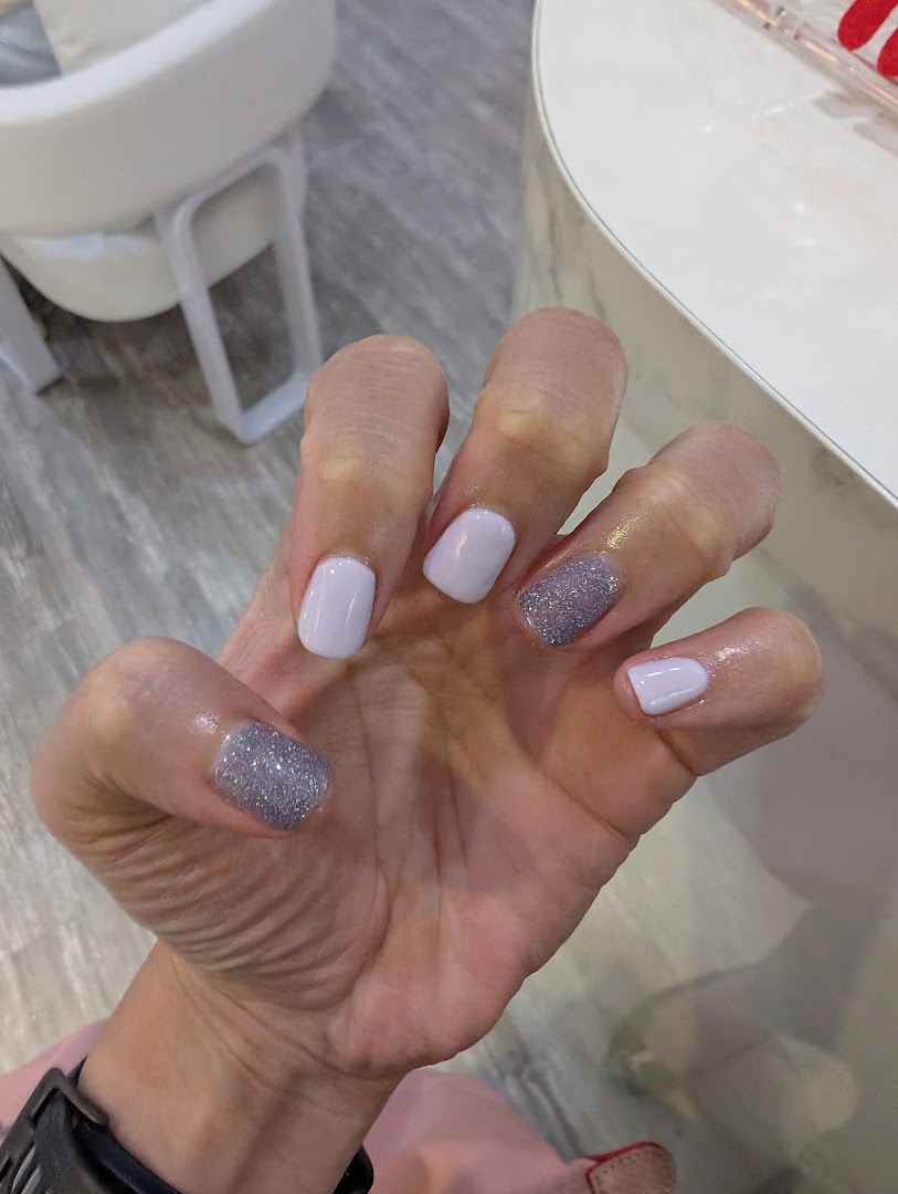 A hand showcasing freshly manicured nails with light purple and glitter polish.