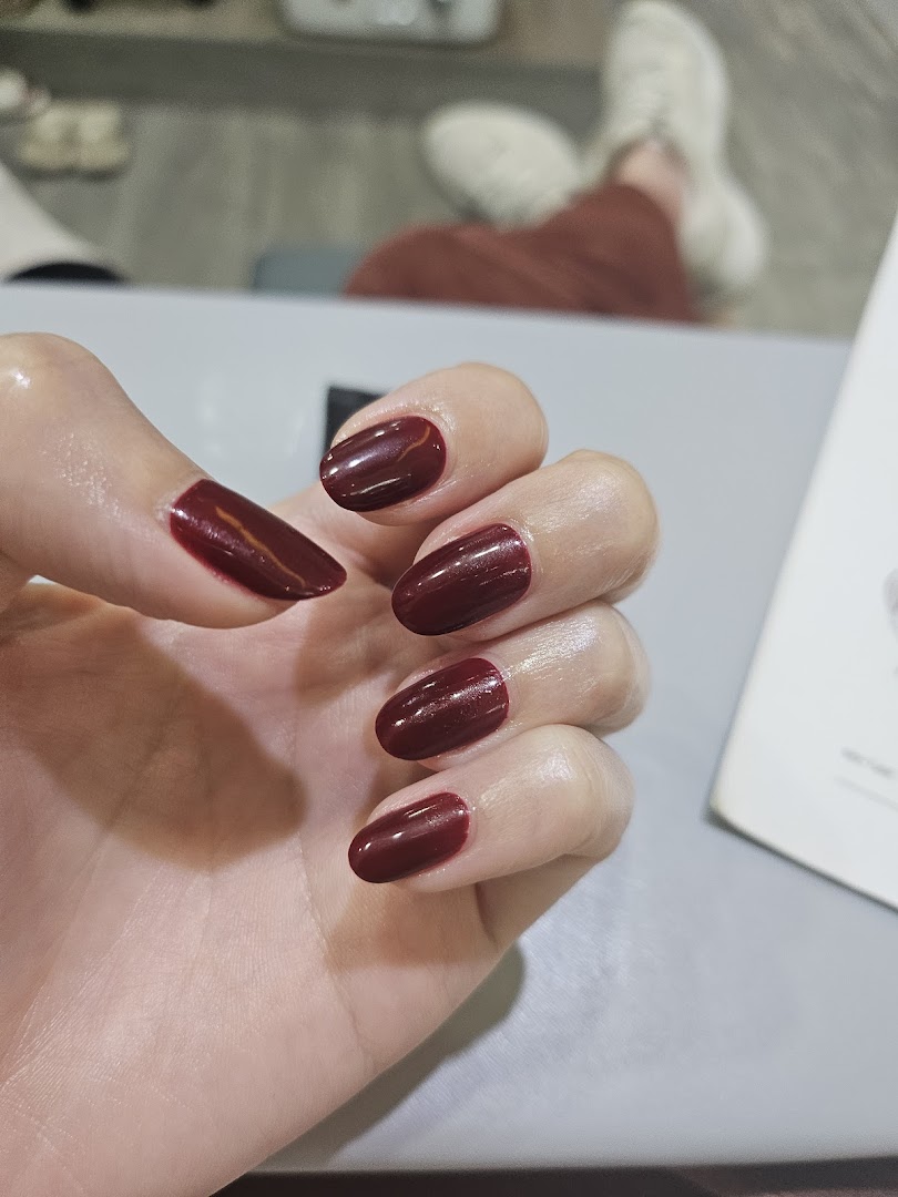 A close-up of a hand showcasing freshly painted dark red nails, likely after a salon service.