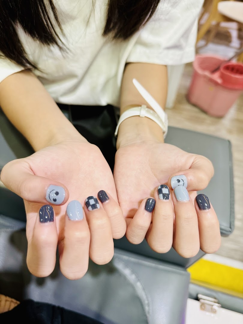 Close-up of hands showcasing a fresh manicure with grey, black, and checkered nail art designs.