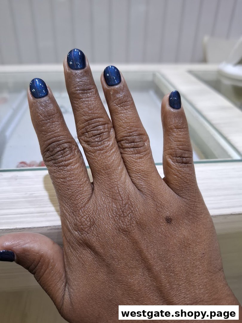 A close-up of a hand showcasing freshly manicured nails with a shimmering blue polish.