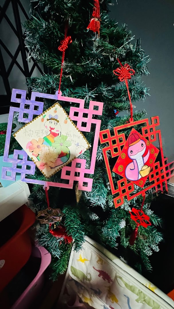 Handcrafted snake-themed ornaments and traditional knots adorn a festive green tree, showcasing student artistry.