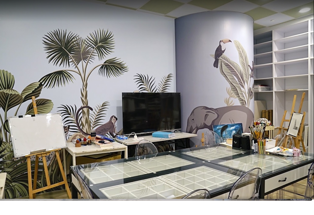 An art studio interior featuring vibrant jungle-themed murals, easels, and a large table with art supplies.