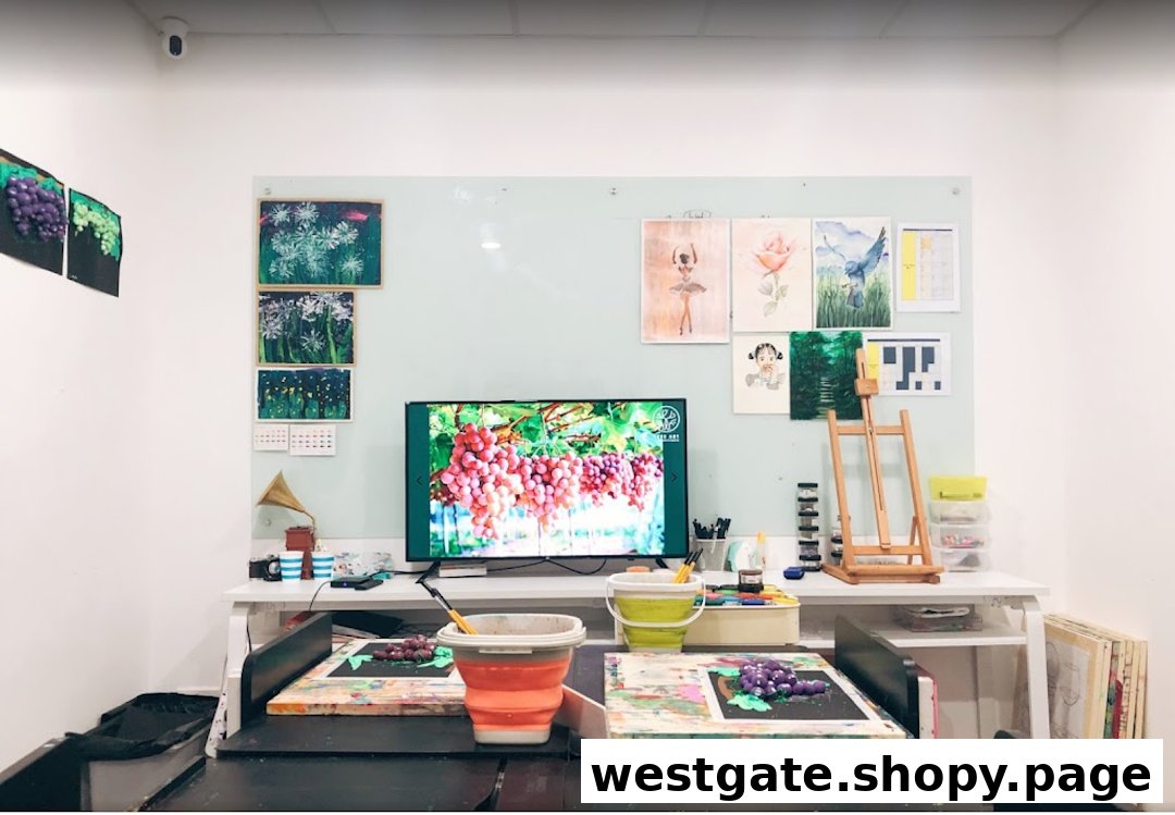 An art studio workspace featuring art supplies, student artworks, a large screen, and creative projects in progress.