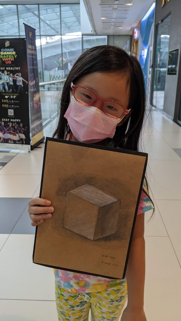 A young student proudly displays their impressive 3D cube artwork, showcasing their artistic talent.