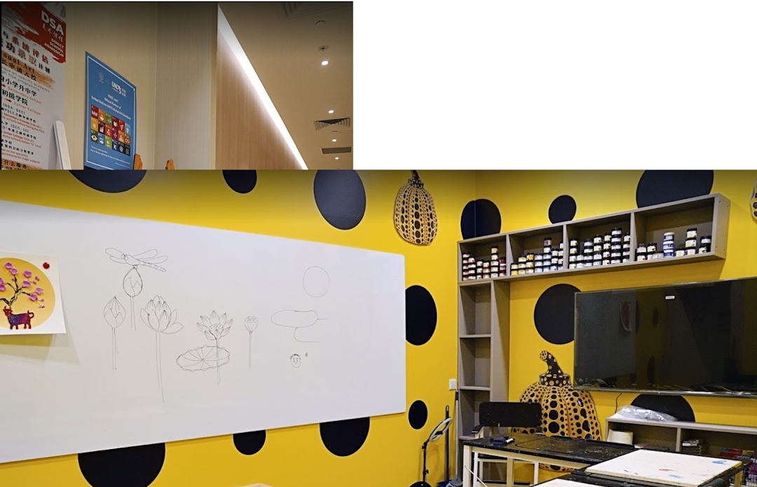 A vibrant art studio interior featuring a whiteboard with drawings, art supplies, and a distinctive yellow polka dot wall.