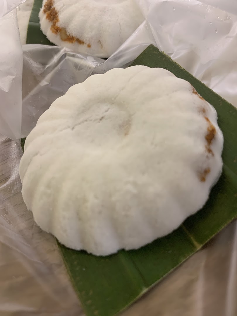 Close-up of a fluffy white coconut cake, served on a banana leaf and wrapped.