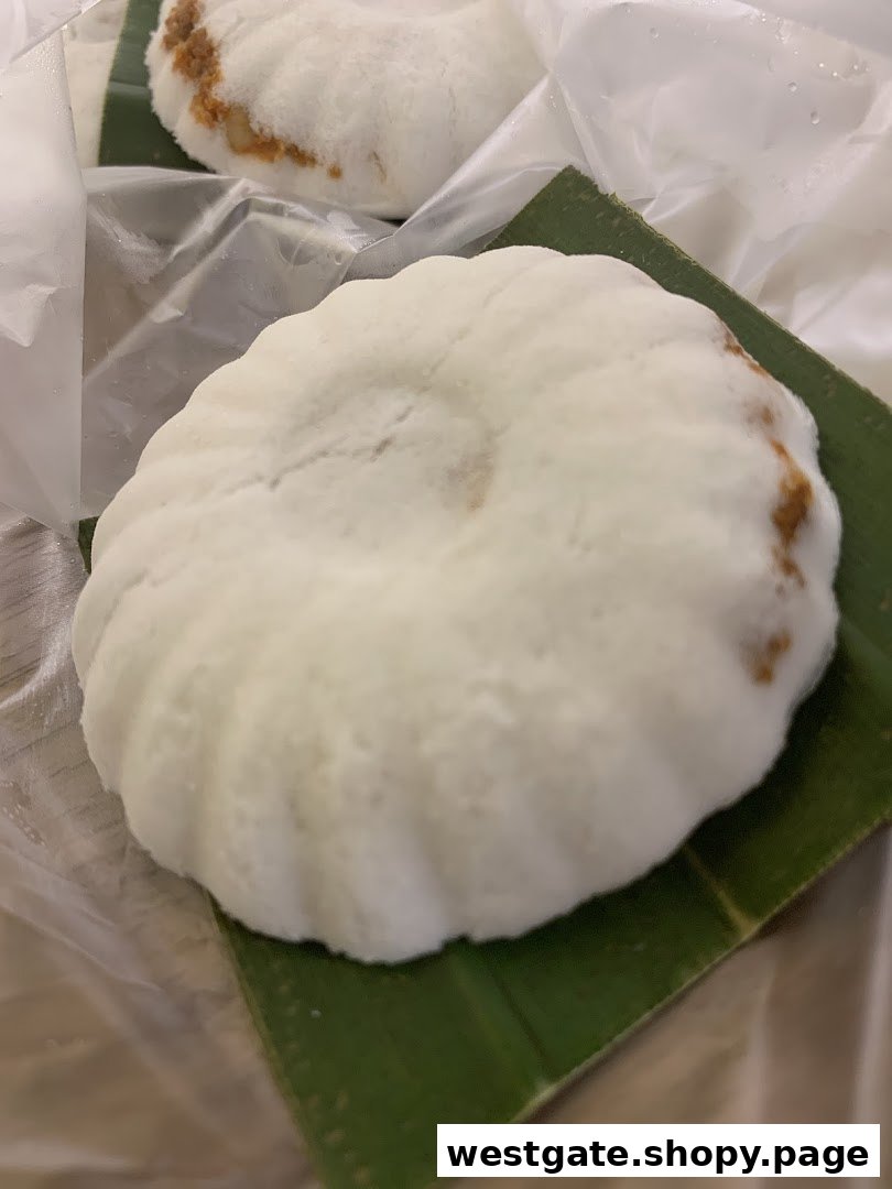 Close-up of a fluffy white coconut cake, served on a banana leaf and wrapped.