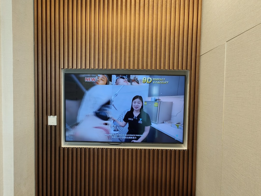 A TV screen mounted on a wooden wall displaying a promotional video for aesthetic treatments.