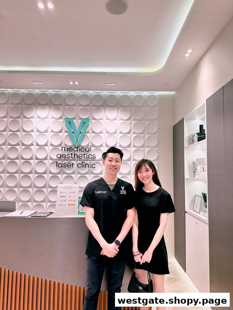 Two individuals stand smiling at the reception area of V Medical Aesthetics Laser Clinic.