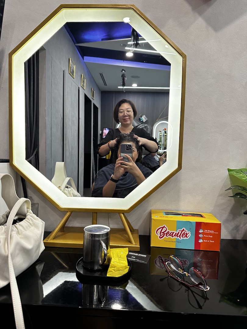 A stylist works on a client's hair, reflected in a modern salon mirror at Vintage Studio.