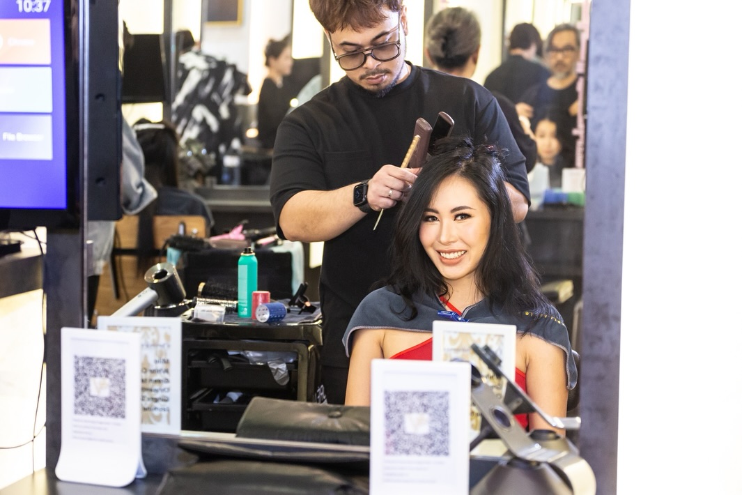A stylist works on a smiling client's hair inside Vintage Studio VS Salon, showcasing professional service.