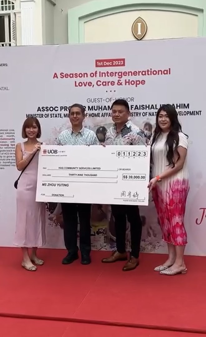 People holding a large donation check for S$39,000 at a community event.