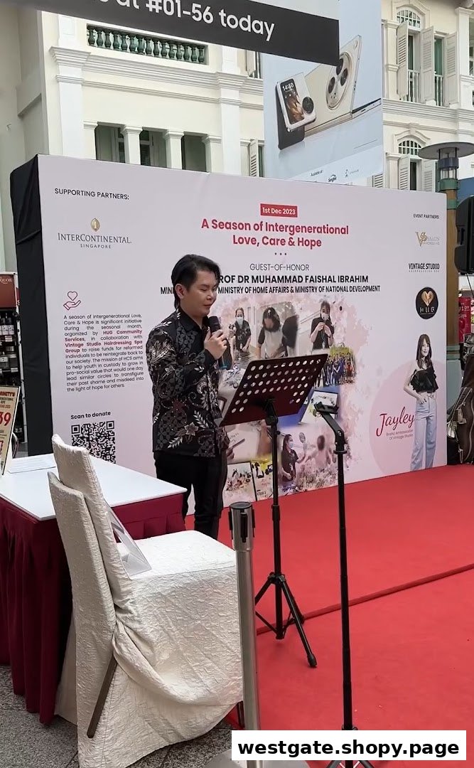 A man speaks at an event with a backdrop promoting 'A Season of Intergenerational Love, Care & Hope' and featuring Vintage Studio.