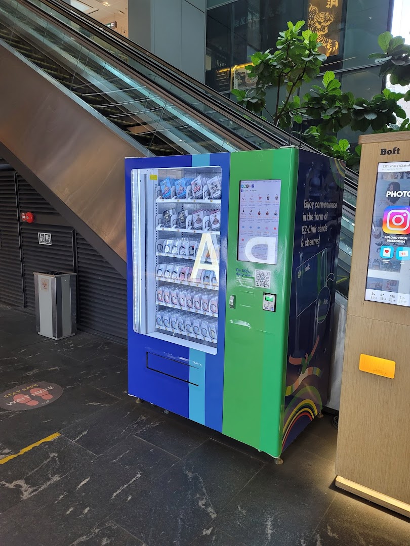 A blue and green EZ-Link vending machine offering cards and charms in a shopping mall.