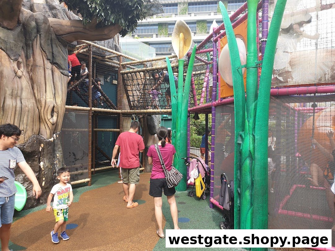 Children and adults enjoy a multi-level indoor playground with a treehouse theme and large plant decorations.